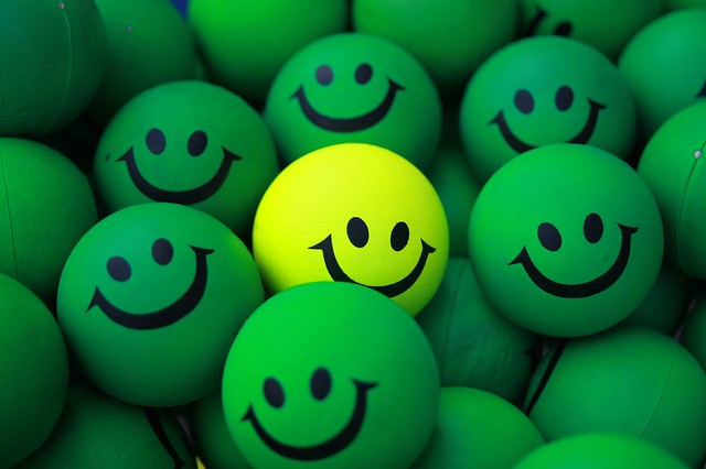 Photo of green circles with smiley faces and one yellow circle with a smiley face