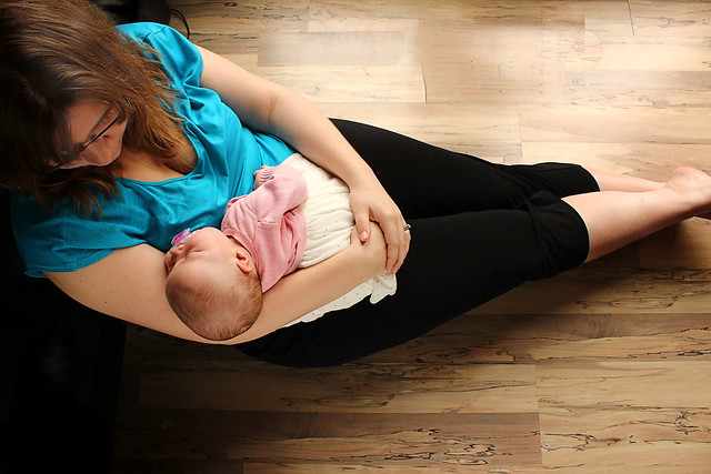 Photo of a mother sitting on the floor holding an infant.