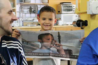 A little boy proudly holds up a beyondcoal.org advertisement bearing his image at a meeting of the Little Village Environmental Justice Organization in Chicago. Photo by Connie Ma via flickr.com.