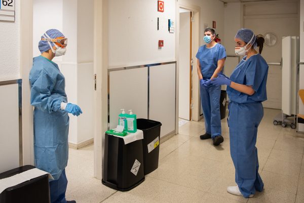 Doctors with masks and scrubs stand in a hospital and talk