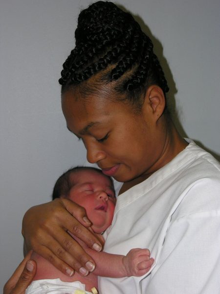 Photo of a Black mother cuddling her newborn baby