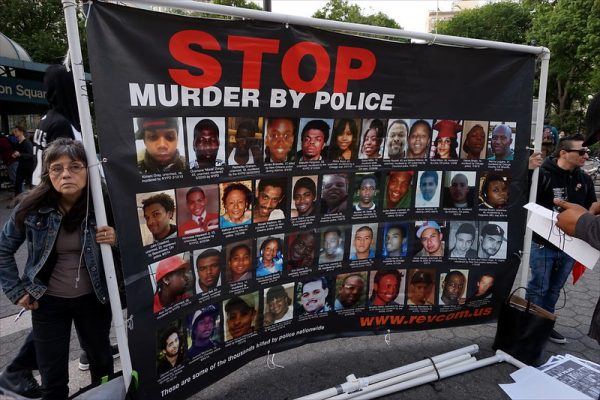 Photo shows a large sign that reads, Stop Murder by Police, and shows pictures of women and girls killed by police.
